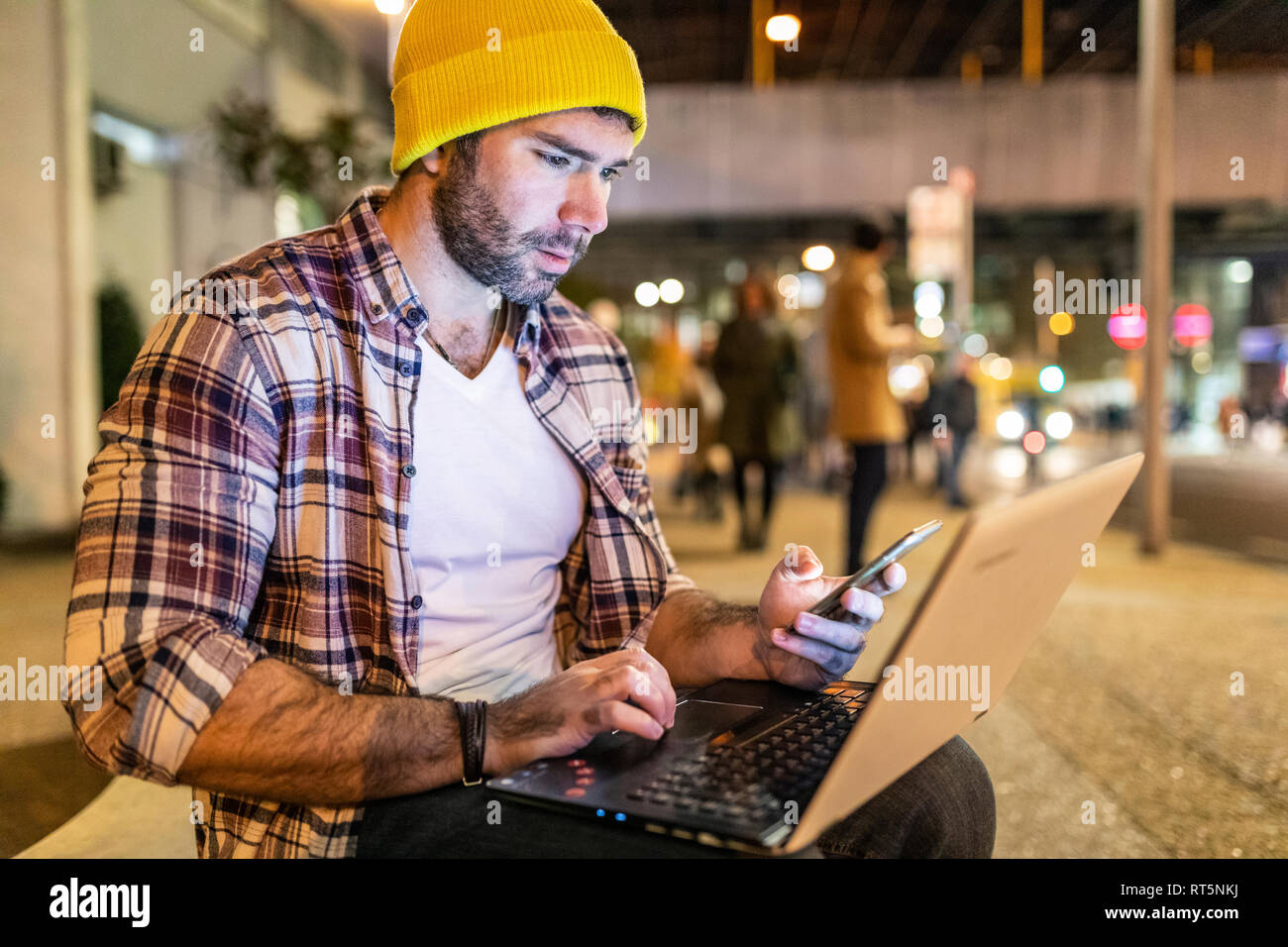 UK, London, man using phone and laptop out in the city at night Stock Photo