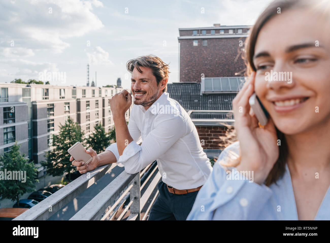 Business people standing on balcony, using smartphone Stock Photo