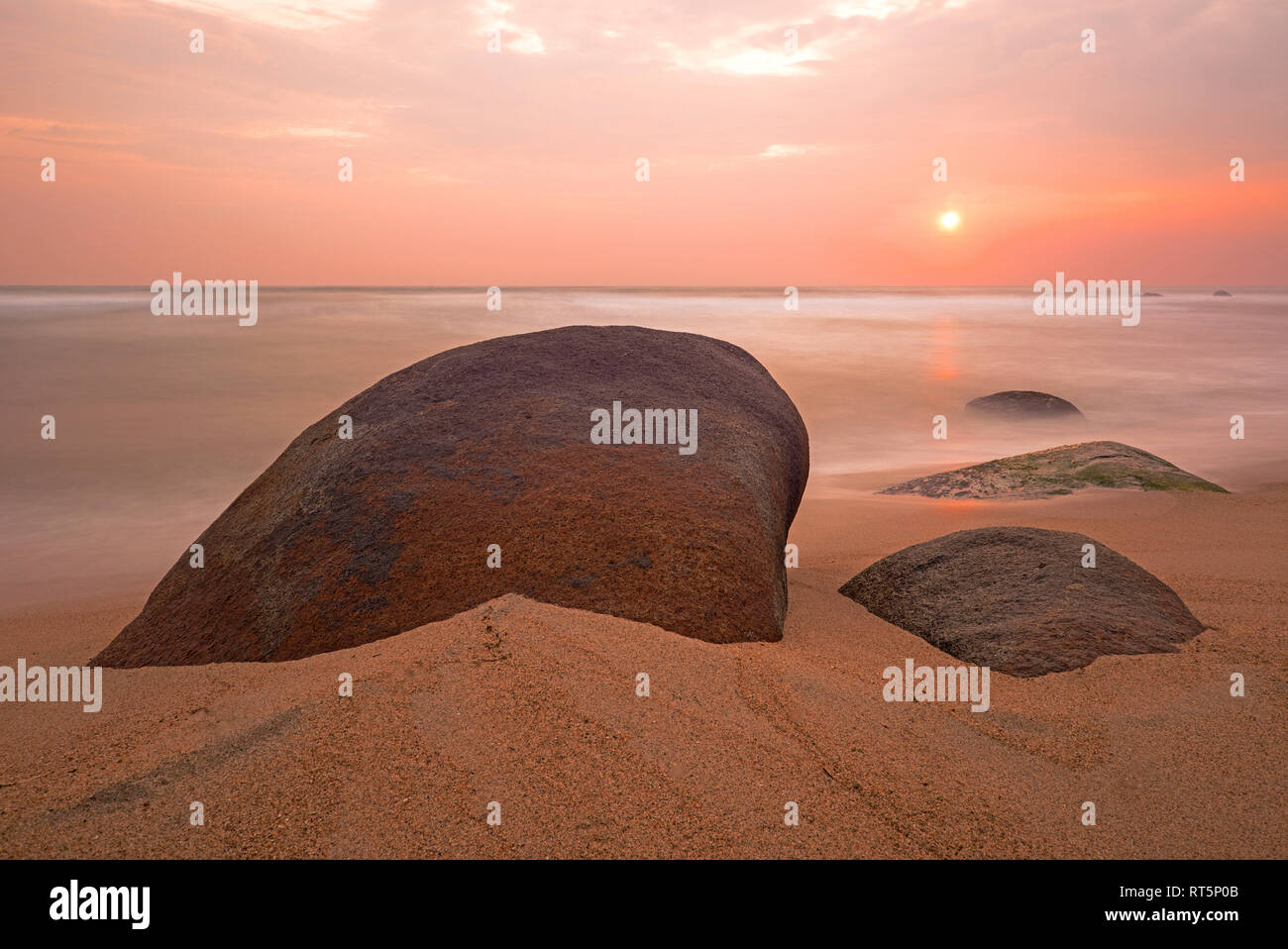 Long exposure photograph of a sunrise along the beach in Tayrona national park famous for its rock boulders near Cartagena, Colombia. Stock Photo