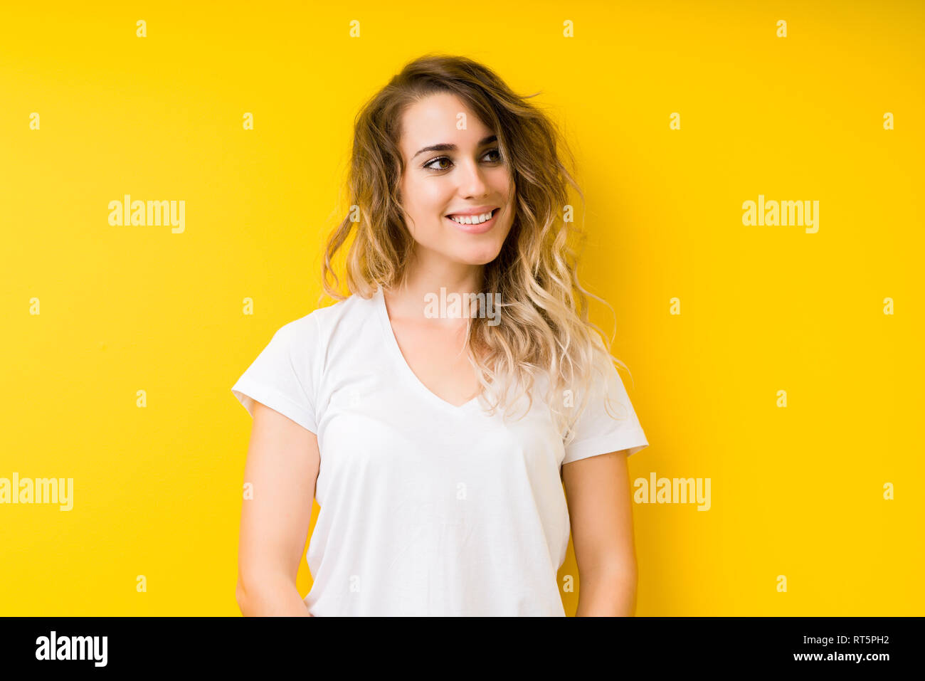 Young beautiful blonde woman over yellow background looking away to ...