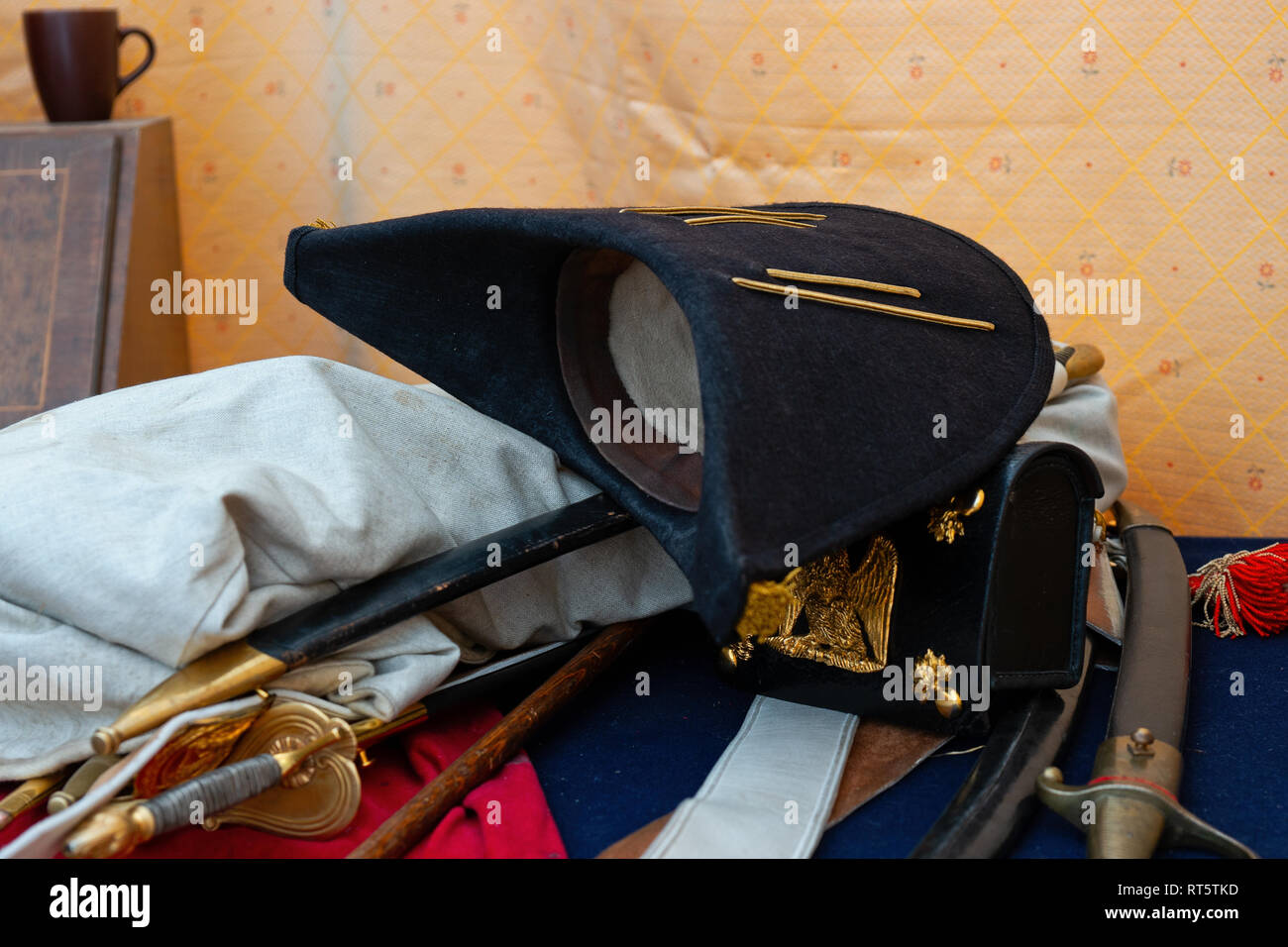 Vintage cocked hat, cartridges pouch, a pile of swords, blades and scabbards on a table. Military items of Napoleon-era wars Stock Photo