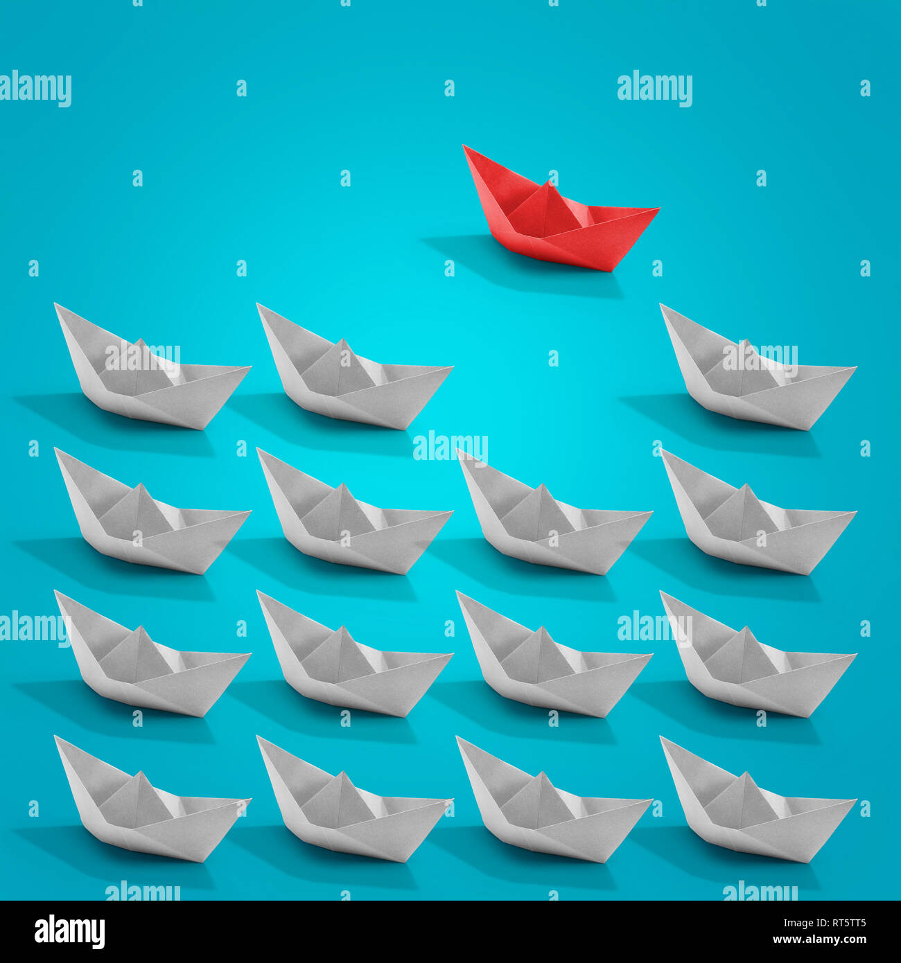 Flotting paper boat origami with a red one on turquoise color background. Business and solution concept Stock Photo