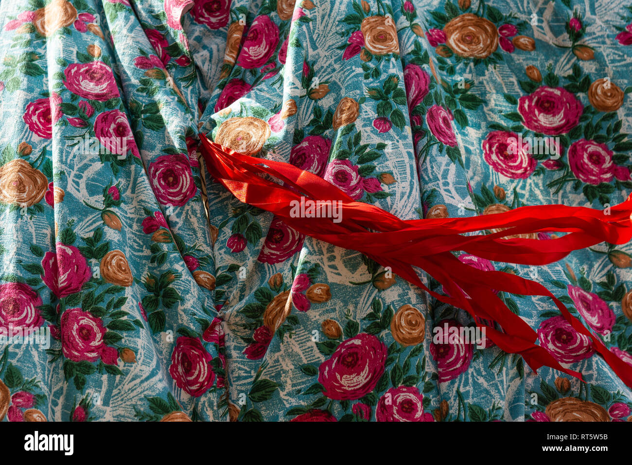 Bird's eye fabric decorated with red and yellow rose flower images and red ribbons waves in the wind. Beautiful designer pattern or background Stock Photo