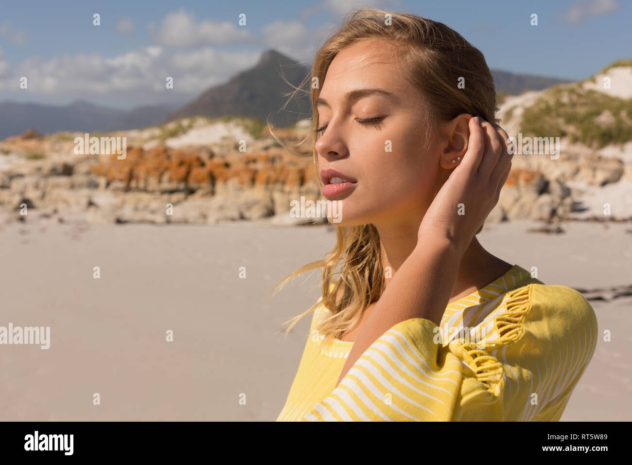 Woman standing with eyes closed on the beach Stock Photo