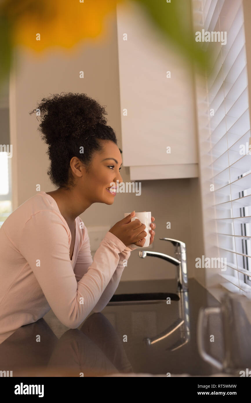 Beautiful woman having coffee in kitchen at home Stock Photo