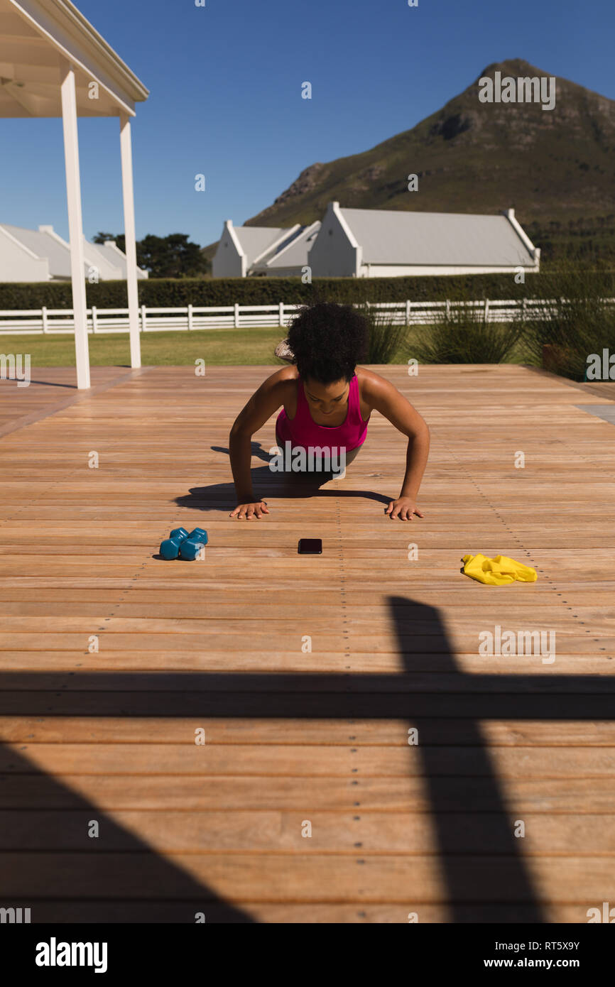 Woman performing push-up exercise in the backyard of home Stock Photo