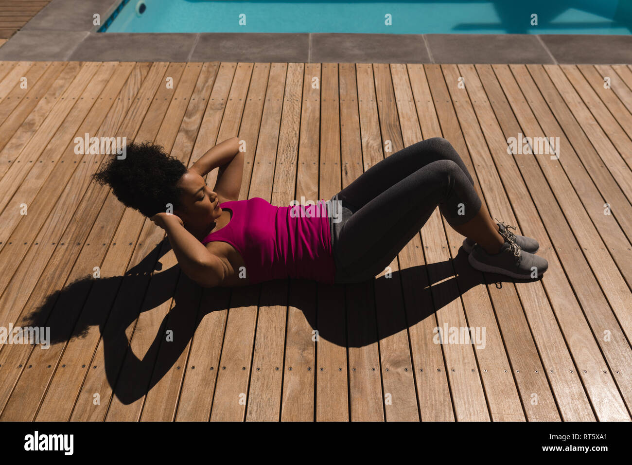 Woman performing crunch exercise in the backyard of home Stock Photo