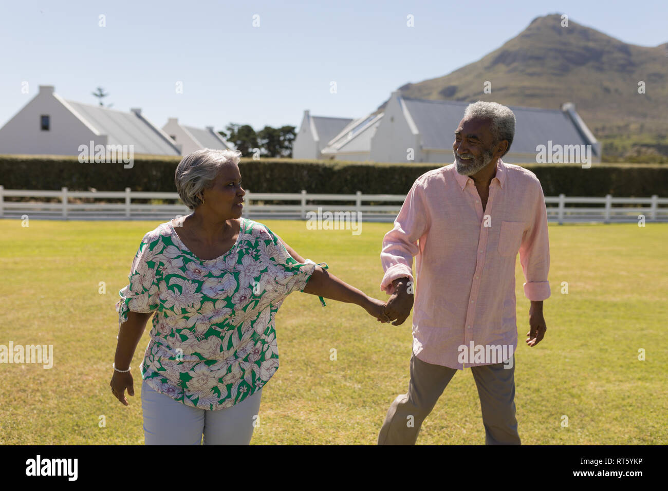 Senior couple walking hand in hand in the backyard Stock Photo - Alamy