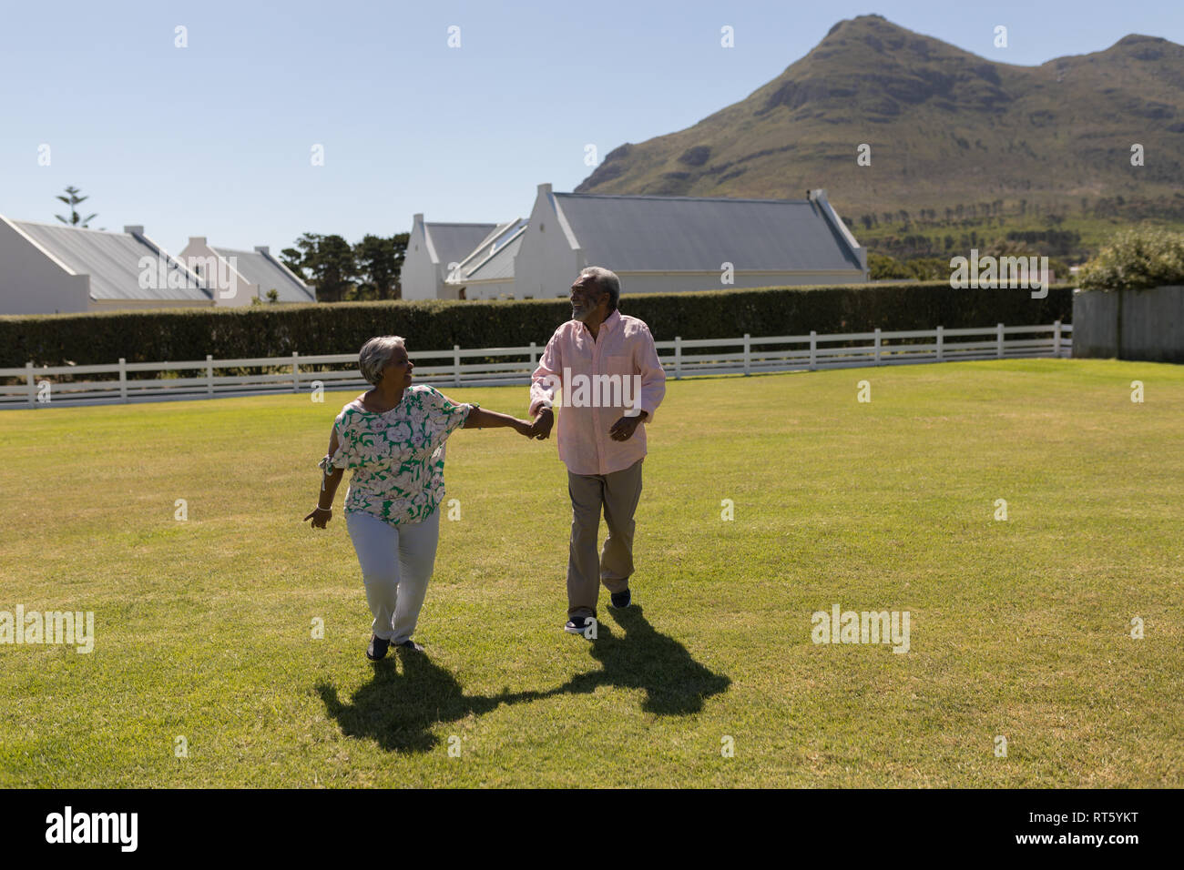 Senior couple walking hand in hand in the backyard Stock Photo - Alamy