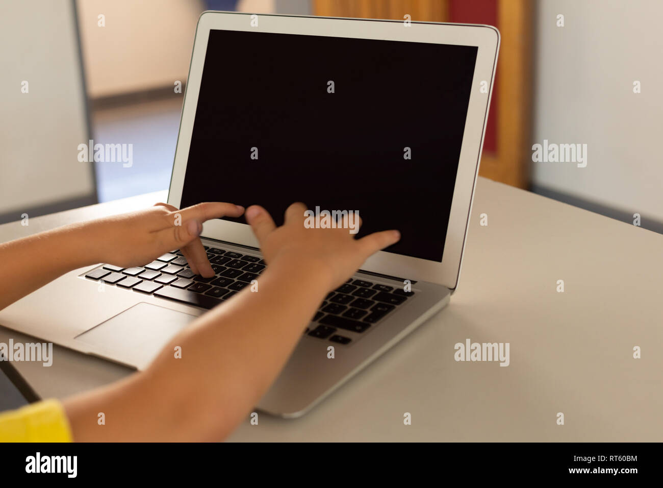 Boy using laptop at desk in a classroom Stock Photo