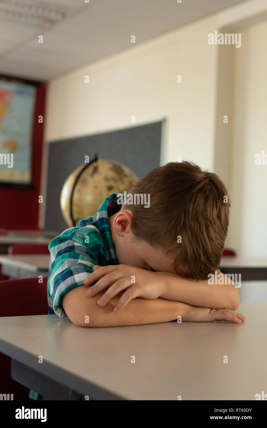 Boy head down at desk in a classroom Stock Photo Alamy