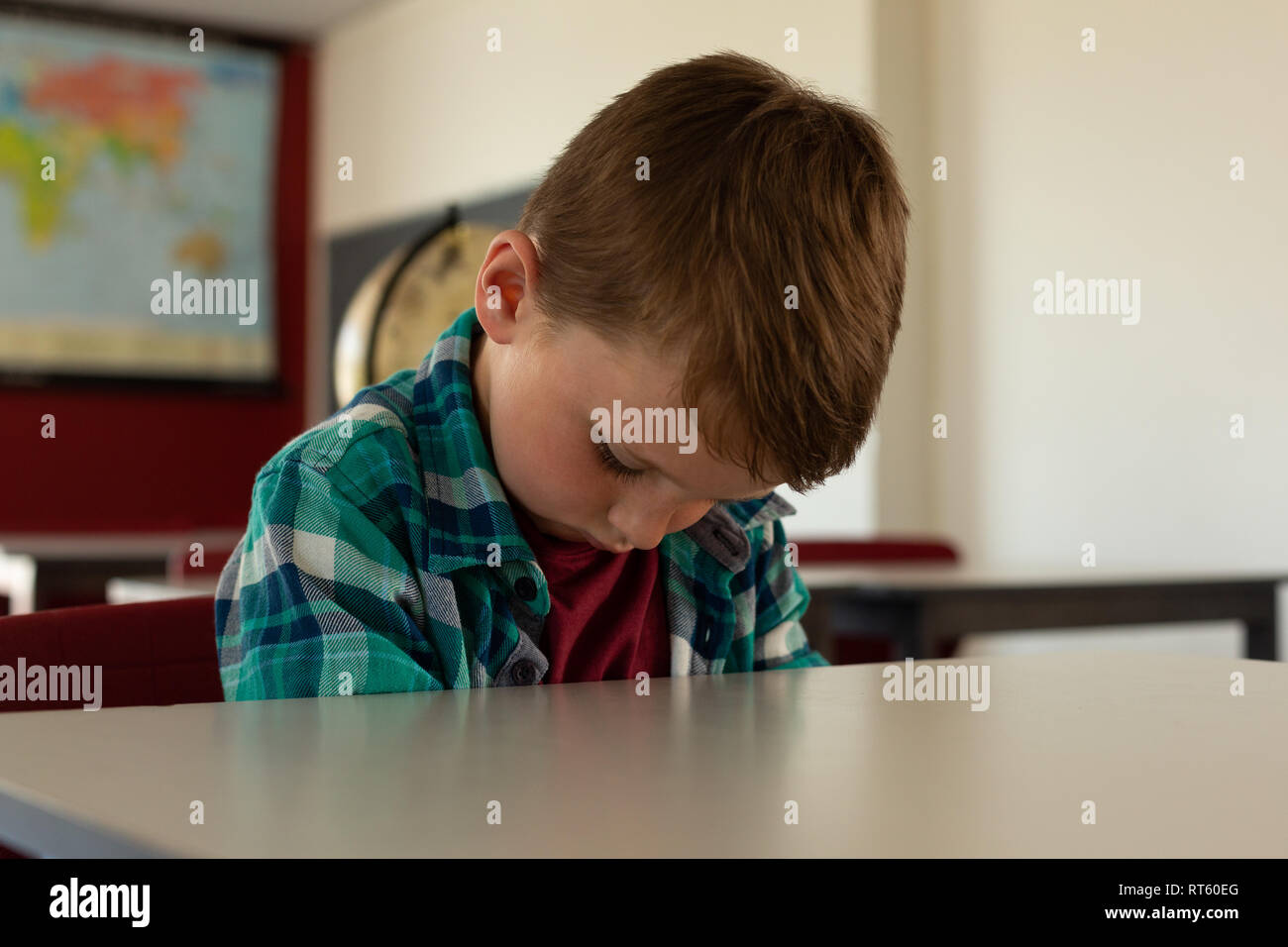Boy sleeping at desk in classroom Stock Photo