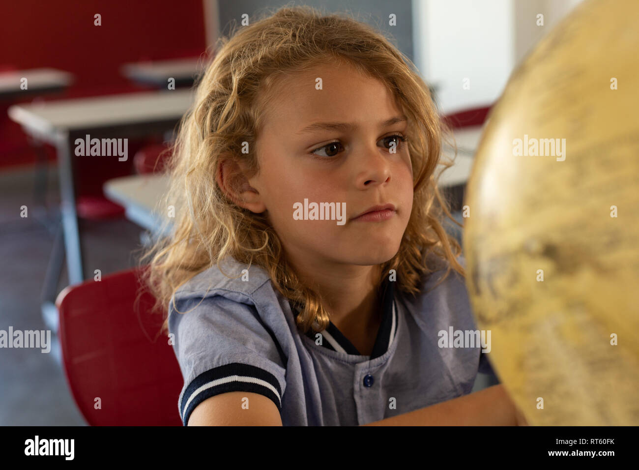 Schoolgirl studying globe at desk in a classroom Stock Photo - Alamy