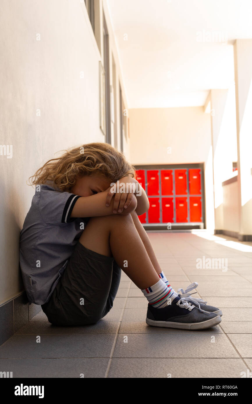 Sad Schoolgirl Sitting On The Floor With His Head Down Stock Photo