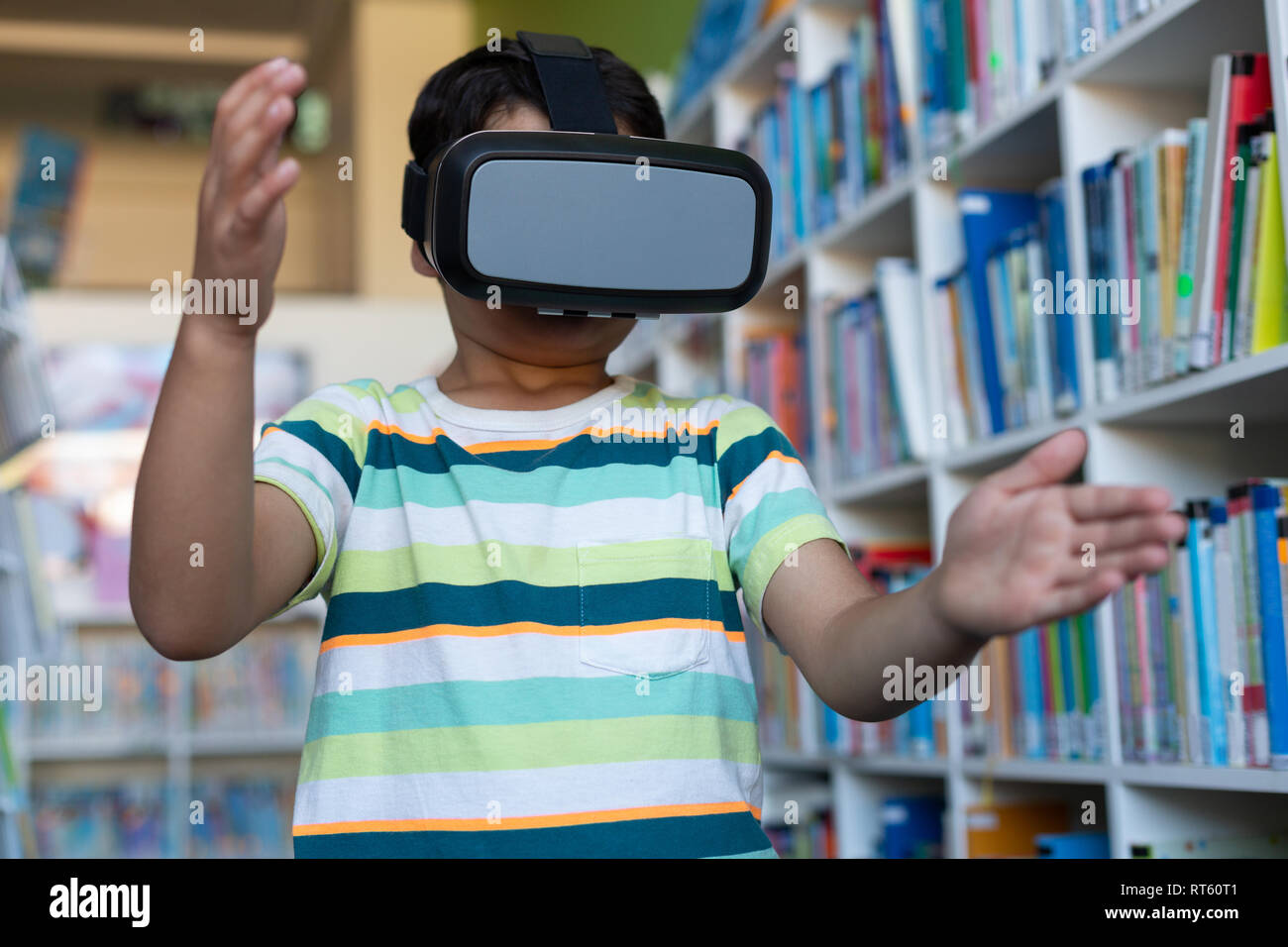 Schoolboy using virtual reality headset in library Stock Photo