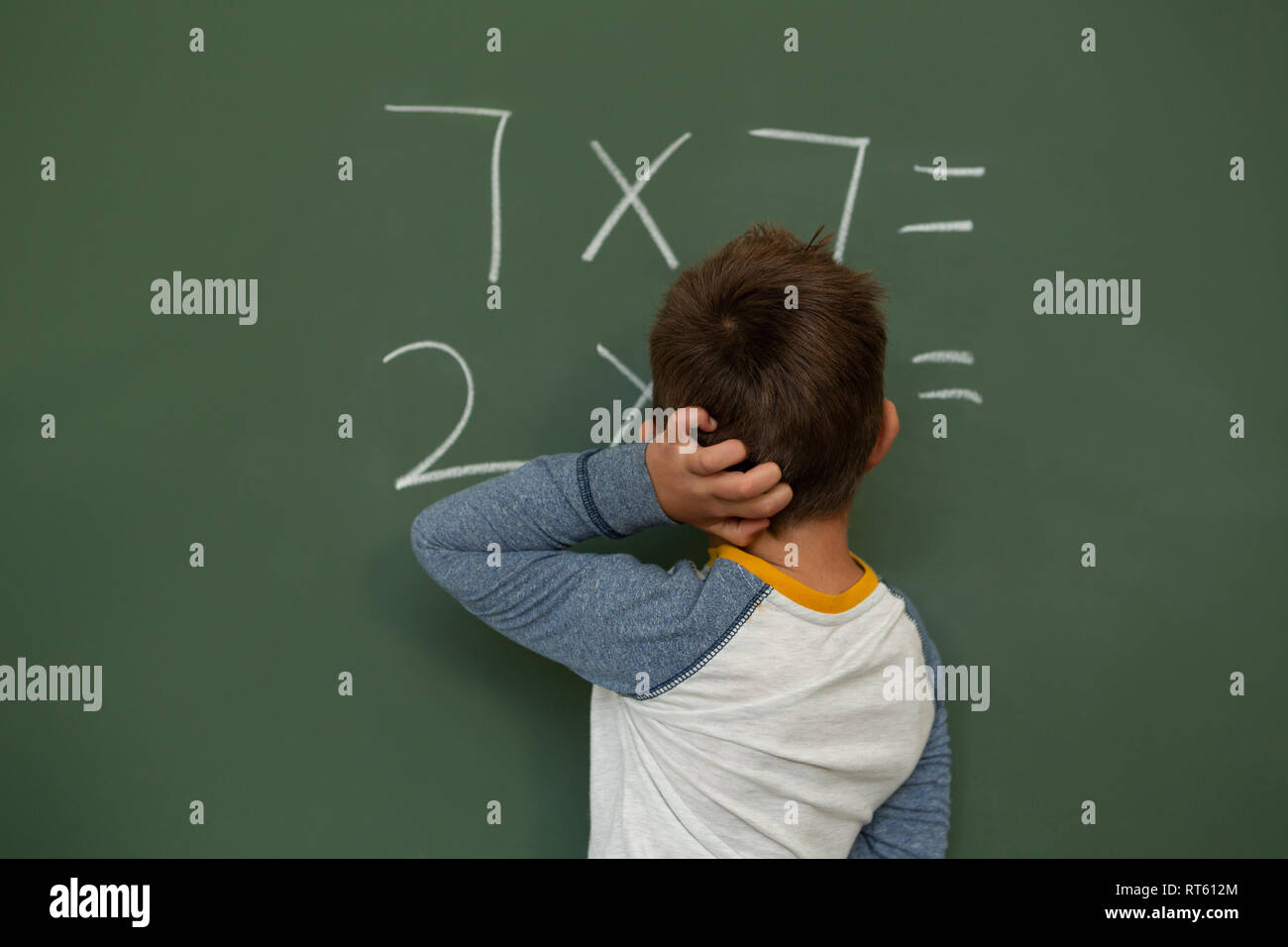 schoolboy doing math on greenboard in a classroom Stock Photo