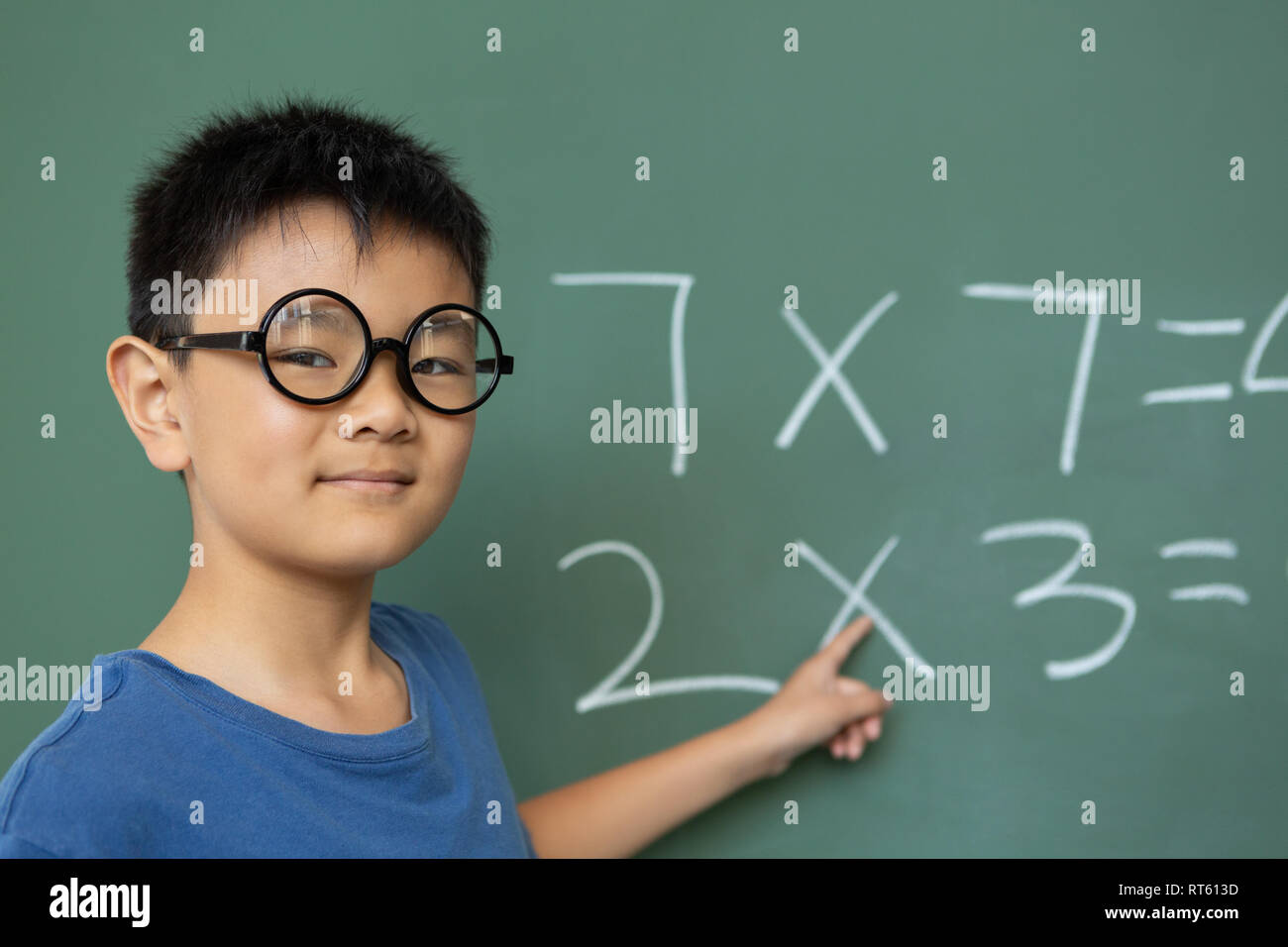 Schoolboy doing math on greenboard in a classroom Stock Photo - Alamy