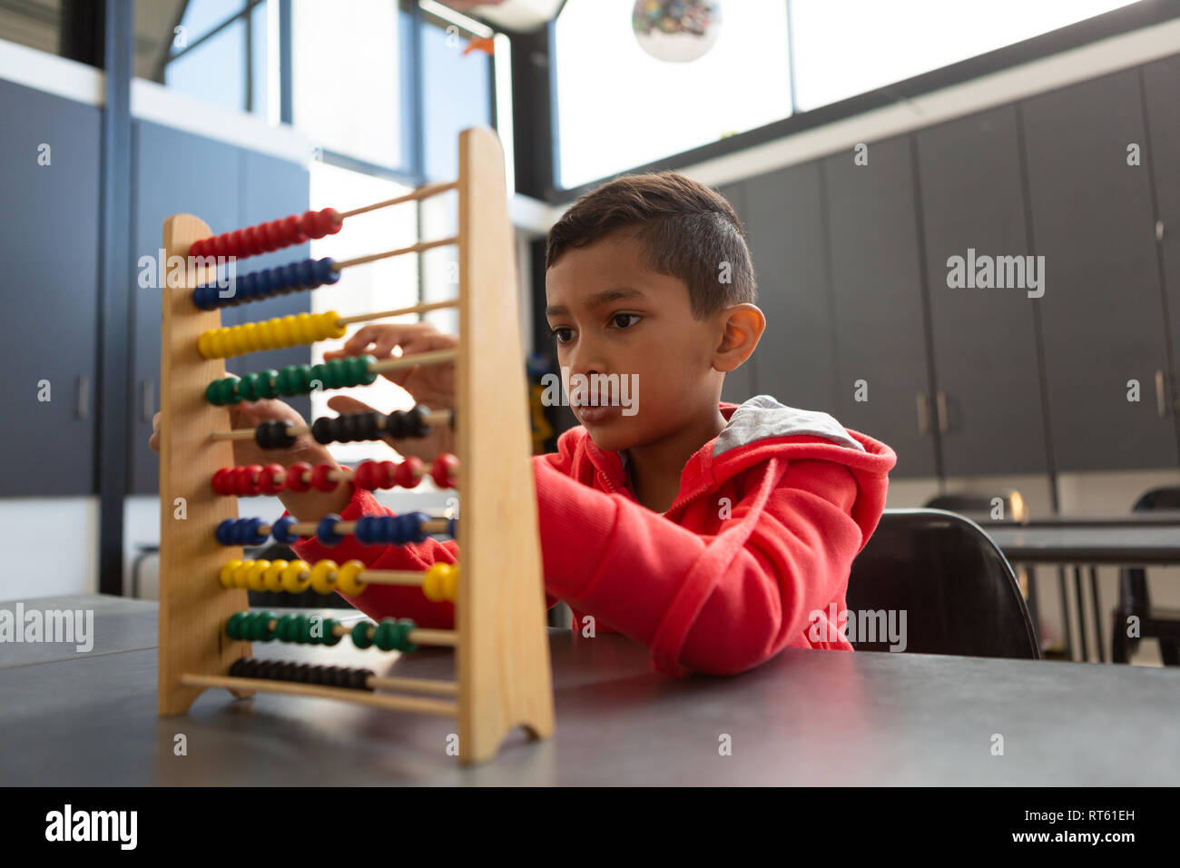 Schoolboy learning math with abacus at desk in a classroom Stock Photo