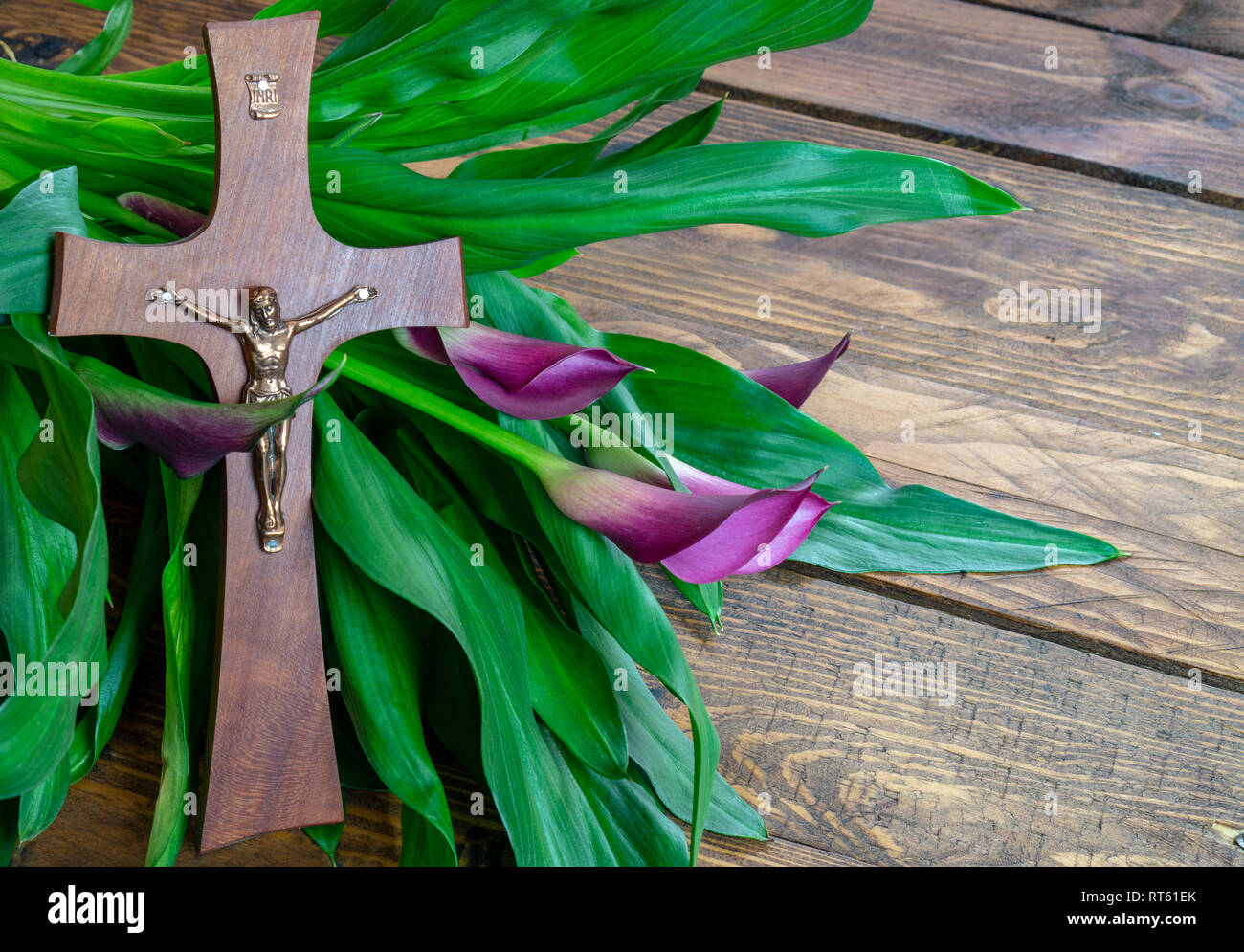 Cross with jesus christ on a wooden background with a purple calla - religious easter lent concept background Stock Photo