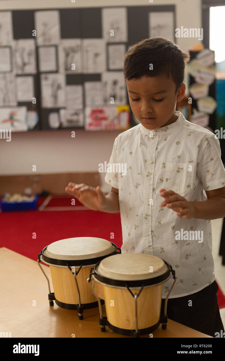 Schoolboy playing bongo in a classroom Stock Photo