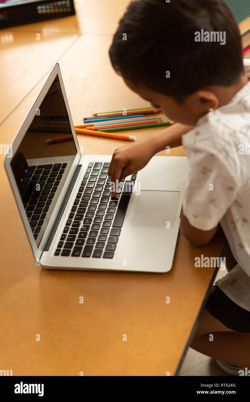 Schoolboy using laptop at table in a classroom Stock Photo - Alamy