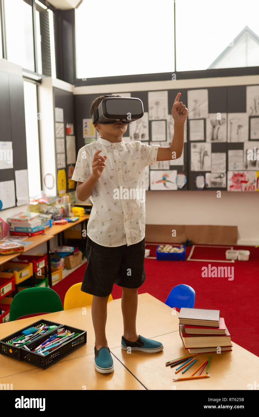Schoolboy using virtual reality headset on a desk in classroom Stock Photo