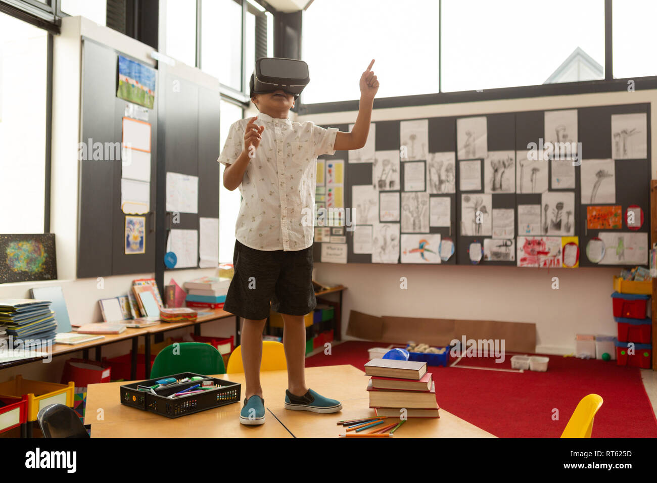 Schoolboy using virtual reality headset on a desk in classroom Stock Photo
