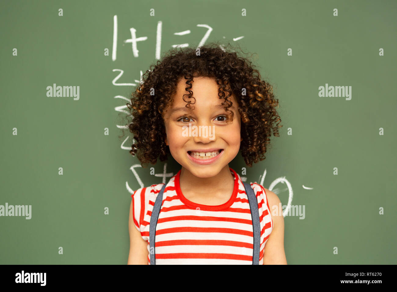 Schoolgirl standing against green board in a classroom at school Stock ...