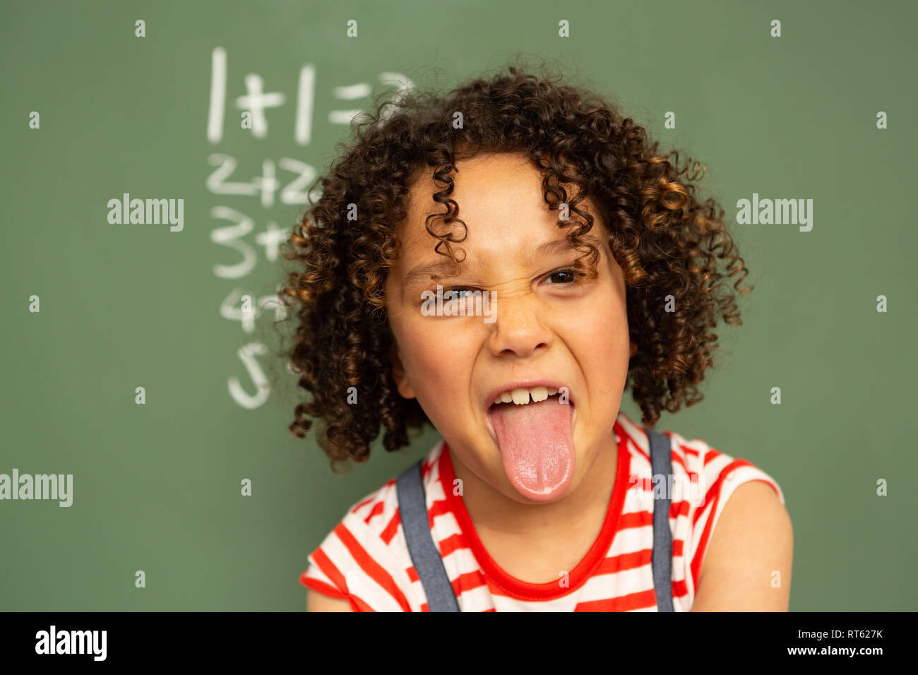 Schoolgirl standing against green board in a classroom at school Stock ...