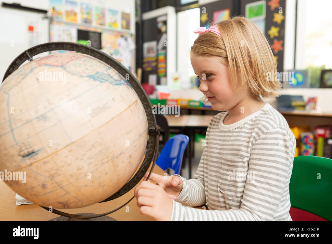 Schoolgirl studying globe at desk in a classroom Stock Photo - Alamy