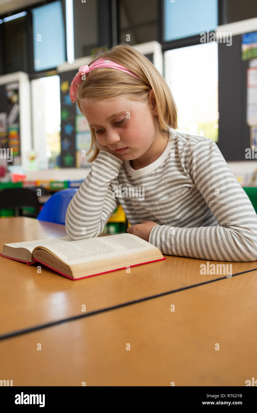 Schoolgirl reading a book in the classroom Stock Photo - Alamy