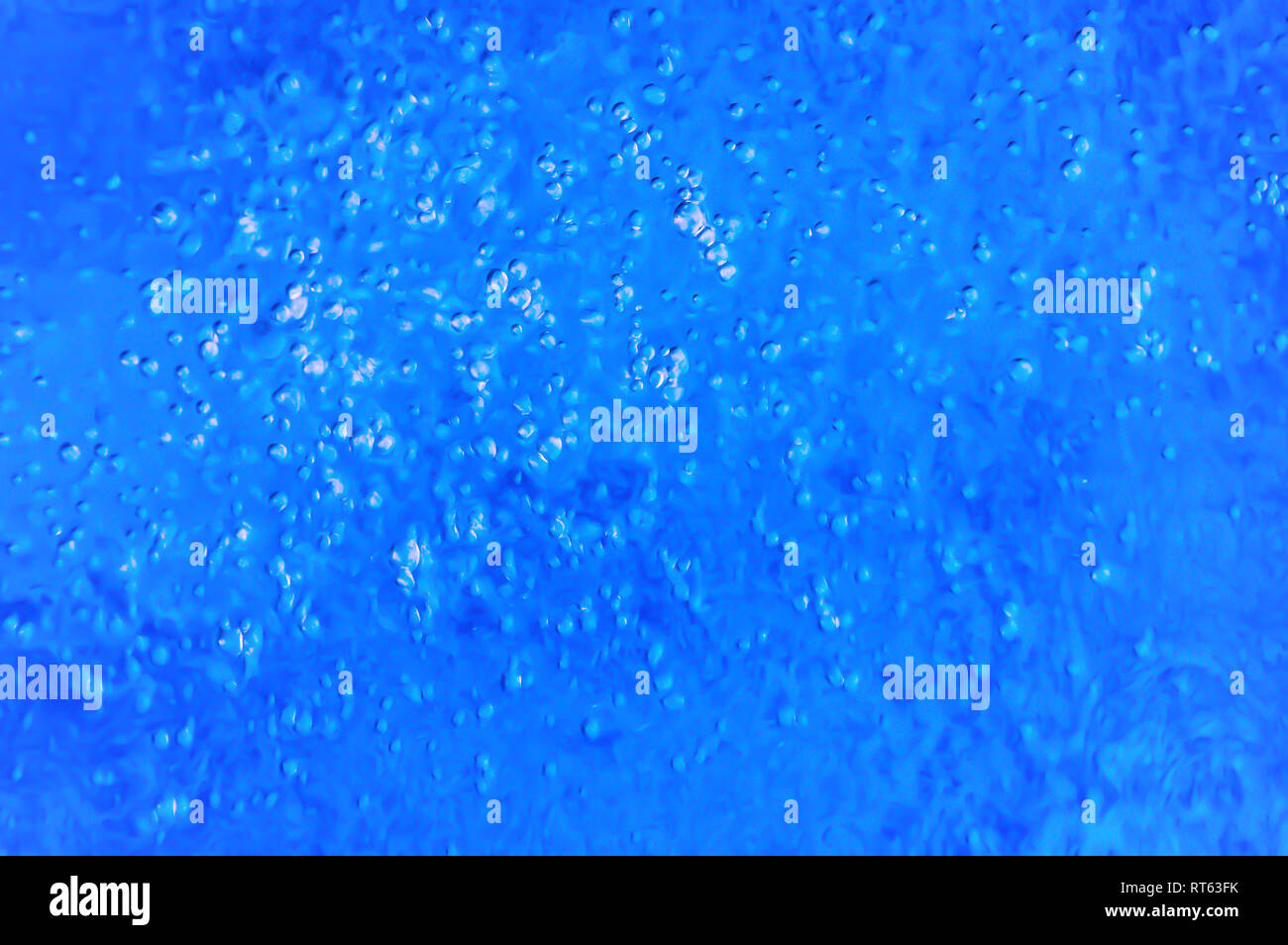 Hundreds of tiny air bubbles rising from the bottom of a swimming pool