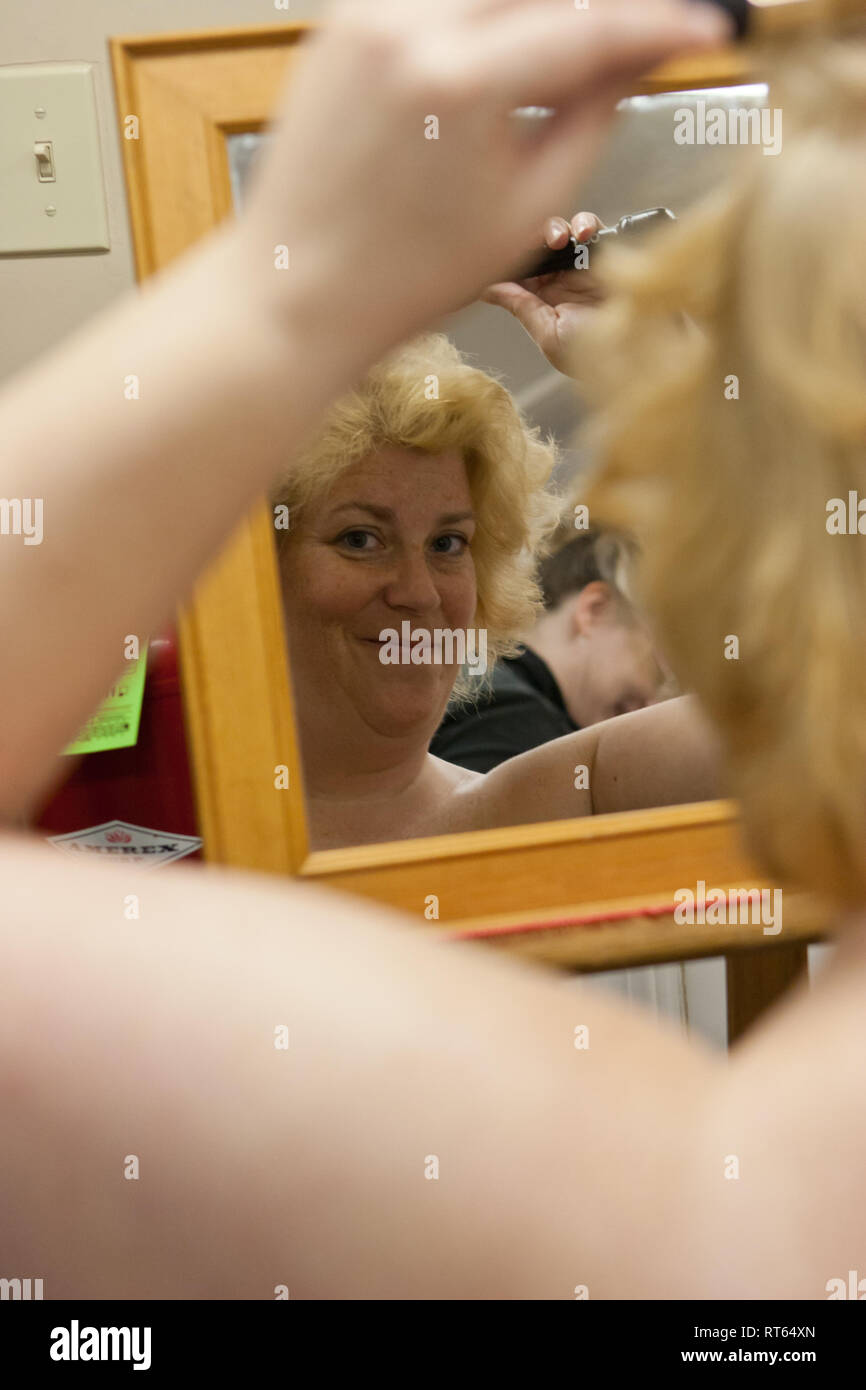 Candid shot of a woman curling her hair in a mirror Stock Photo