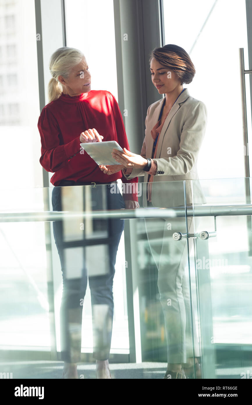 Businesswomen discussing over digital tablet in office building Stock Photo