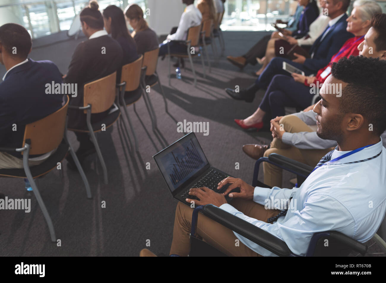 Disabled young businessman using laptop during seminar Stock Photo