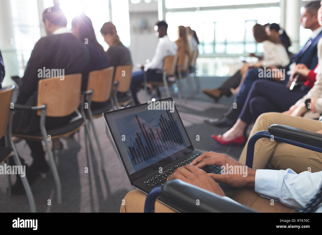 Disabled young businessman using laptop during seminar Stock Photo