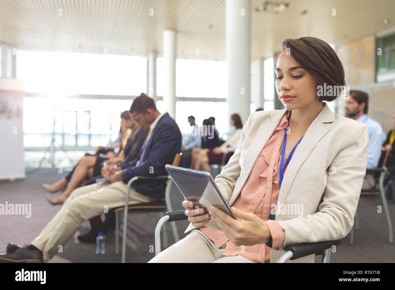 Happy young businesswoman using digital tablet during seminar Stock Photo