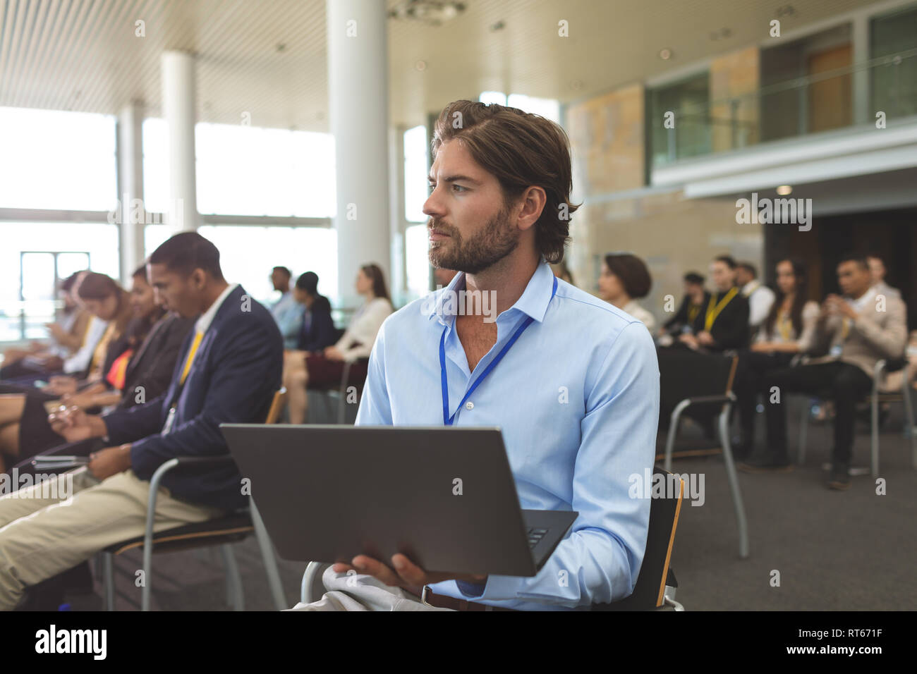 Young businessman with laptop looking away during seminar Stock Photo