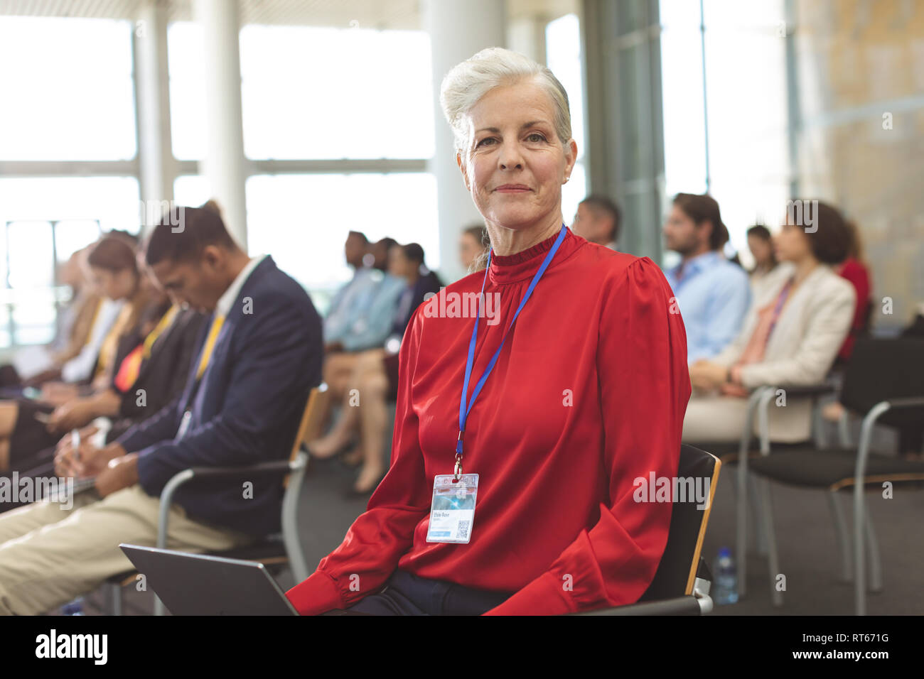 Mature businesswoman with laptop looking at camera during seminar Stock Photo