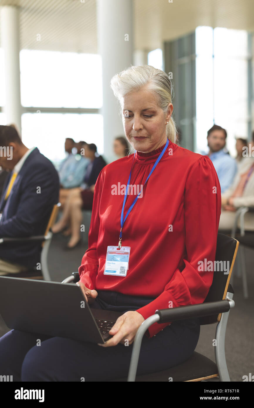 Mature businesswoman using laptop during seminar Stock Photo