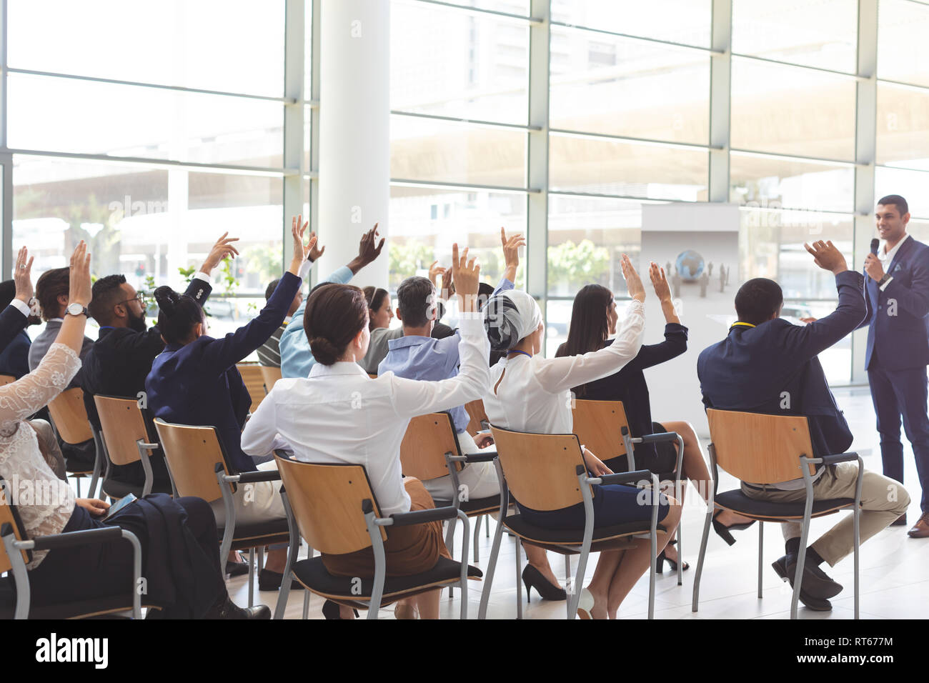 Group of business people raising hands at seminar at conference Stock Photo