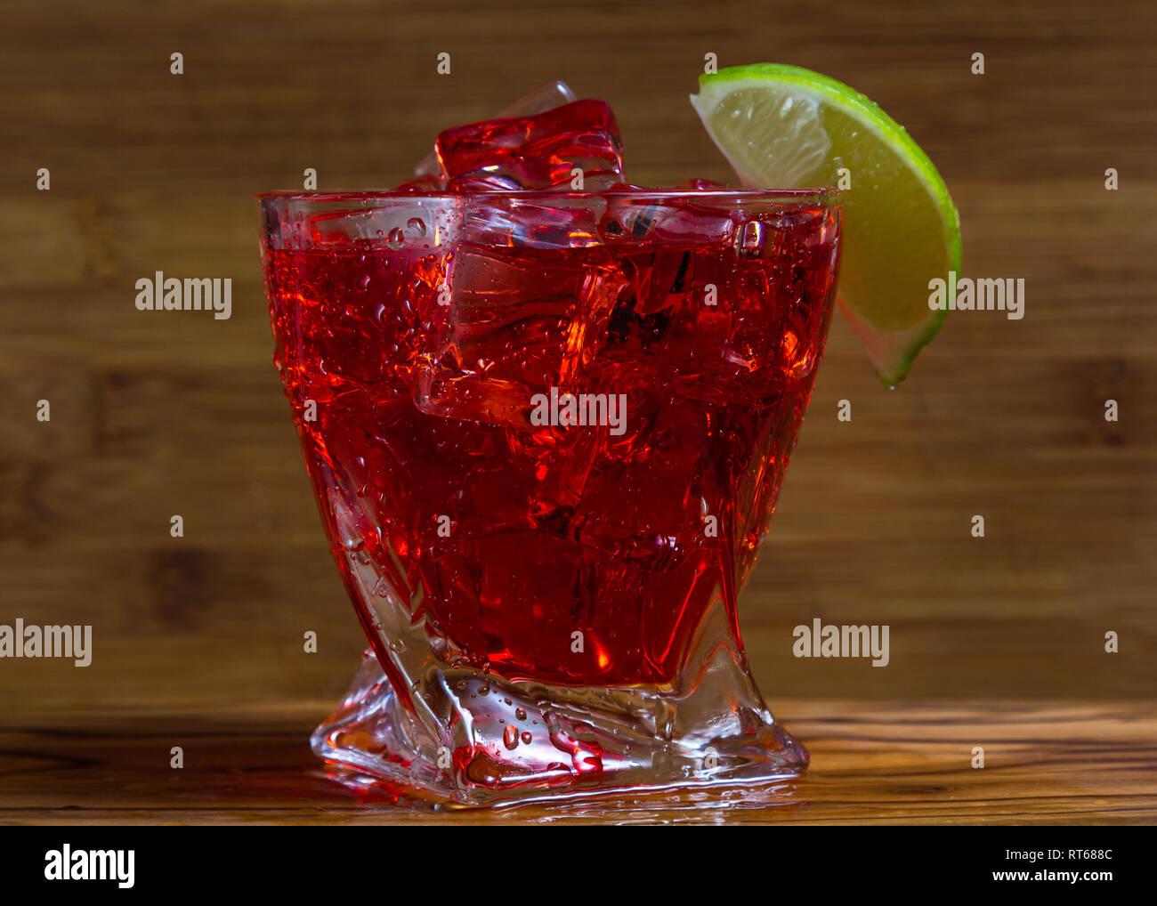 close up of a refreshing classic cocktail with vodka and cranberry juice served on the rocks with a lime wedge garnish with a wooden background Stock Photo