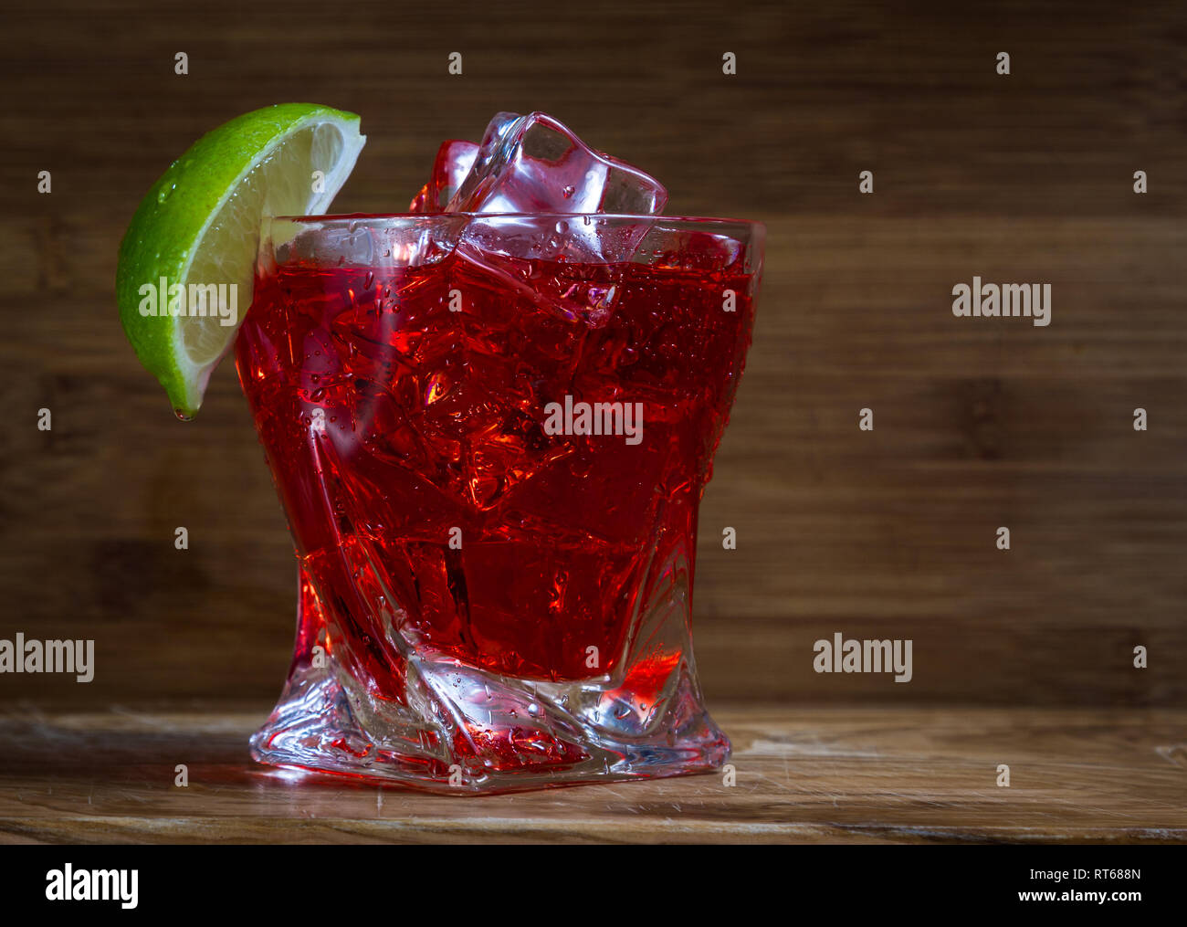 close up of a refreshing classic cocktail with vodka and cranberry juice served on the rocks with a lime wedge garnish with a wooden background Stock Photo