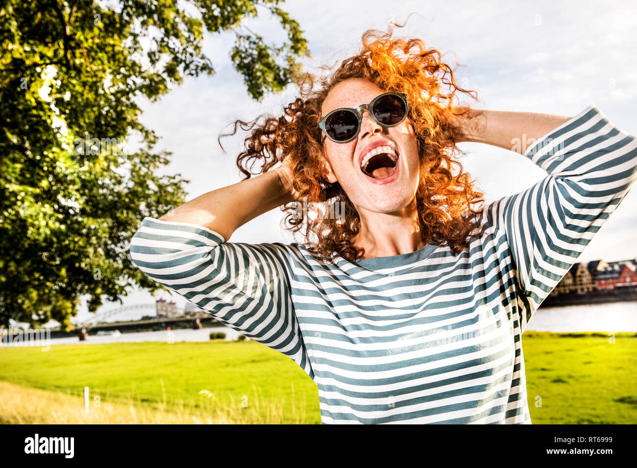 Germany, Cologne, portrait of screaming redheaded young woman wearing sunglasses Stock Photo