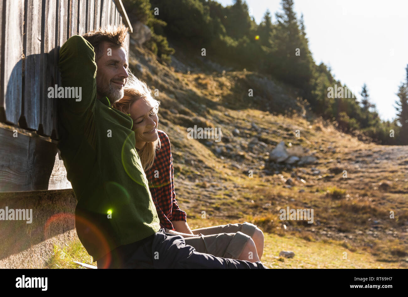 Hiking couple sitting in front of mountain hut, taking a break Stock Photo