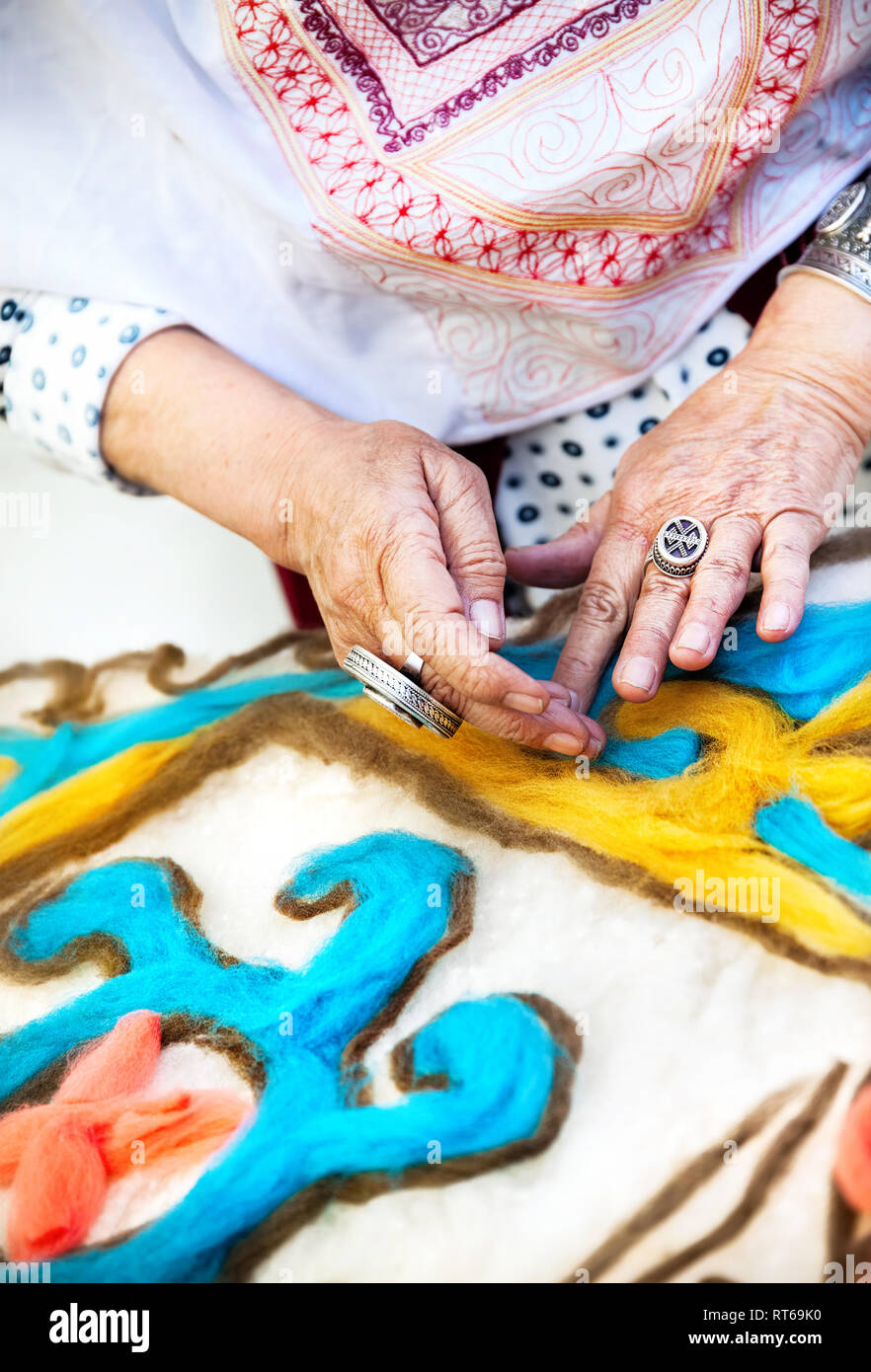 Ethnic woman making pattern on the Kazakh blanket in the market at Nauryz celebration in Almaty, Kazakhstan Stock Photo