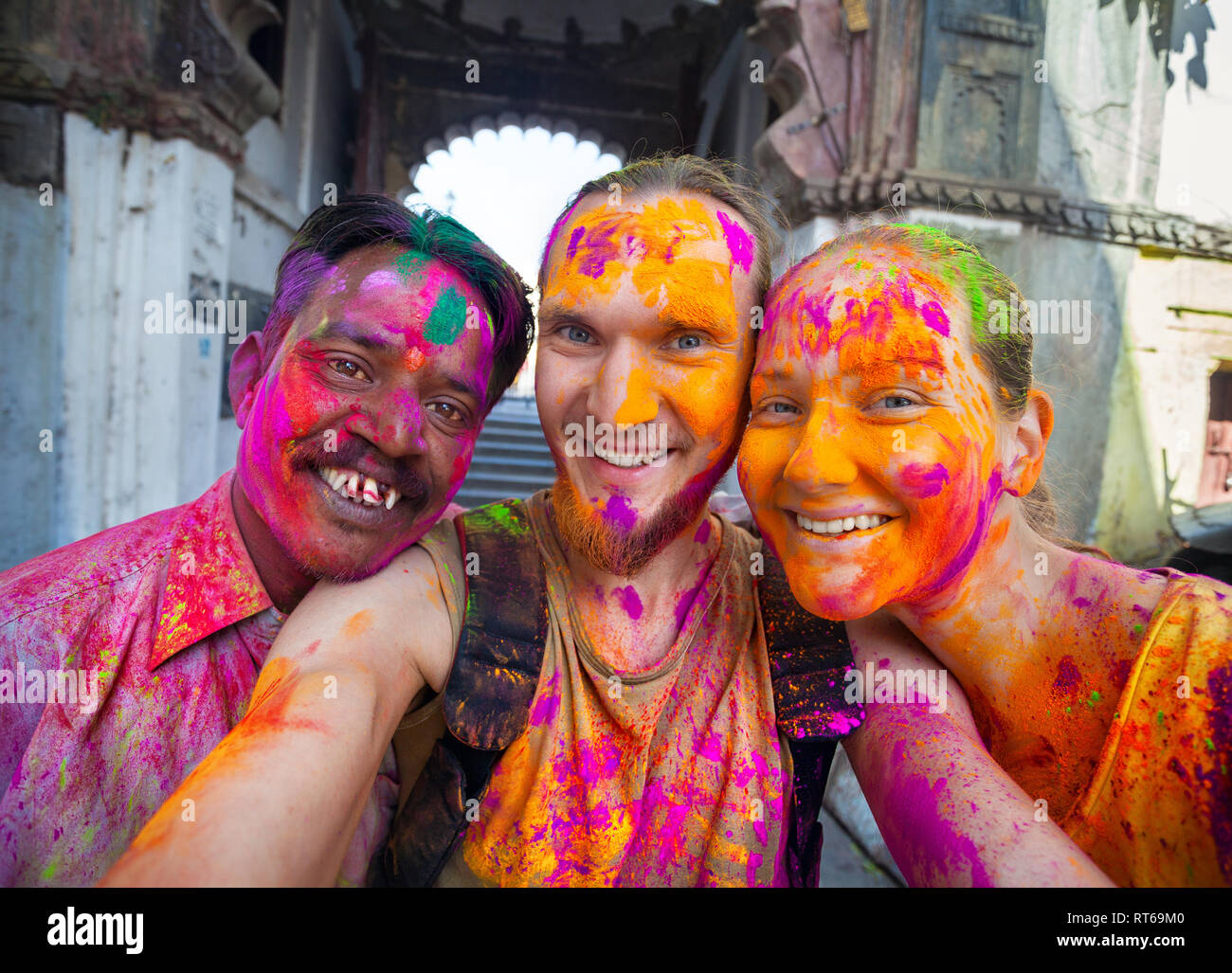 Udaipur, India - March 6, 2015: Selfie photo of Indian man and foreign couple with painted face celebrating the colorful festival of Holi on the stree Stock Photo