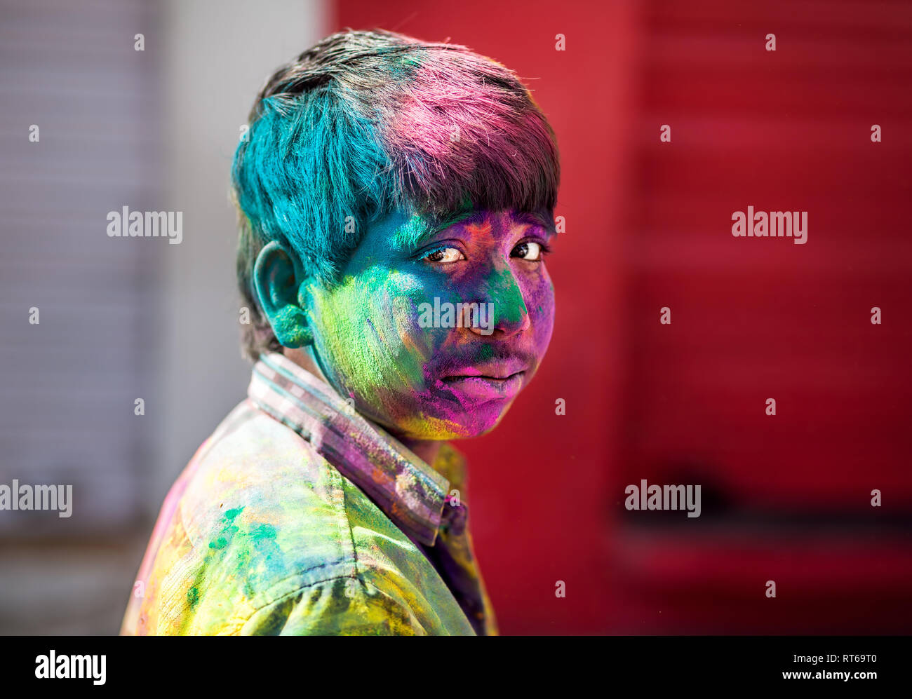 Udaipur, India - March 6, 2015: Portrait of Indian boy with painted face celebrating the colorful festival of Holi on the street. Stock Photo