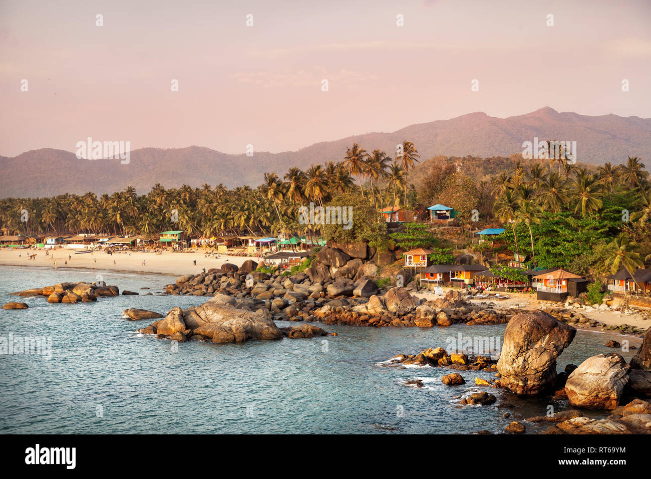 Beautiful view of tropical sunset beach with bungalow and coconut palm trees at Palolem in Goa, India Stock Photo