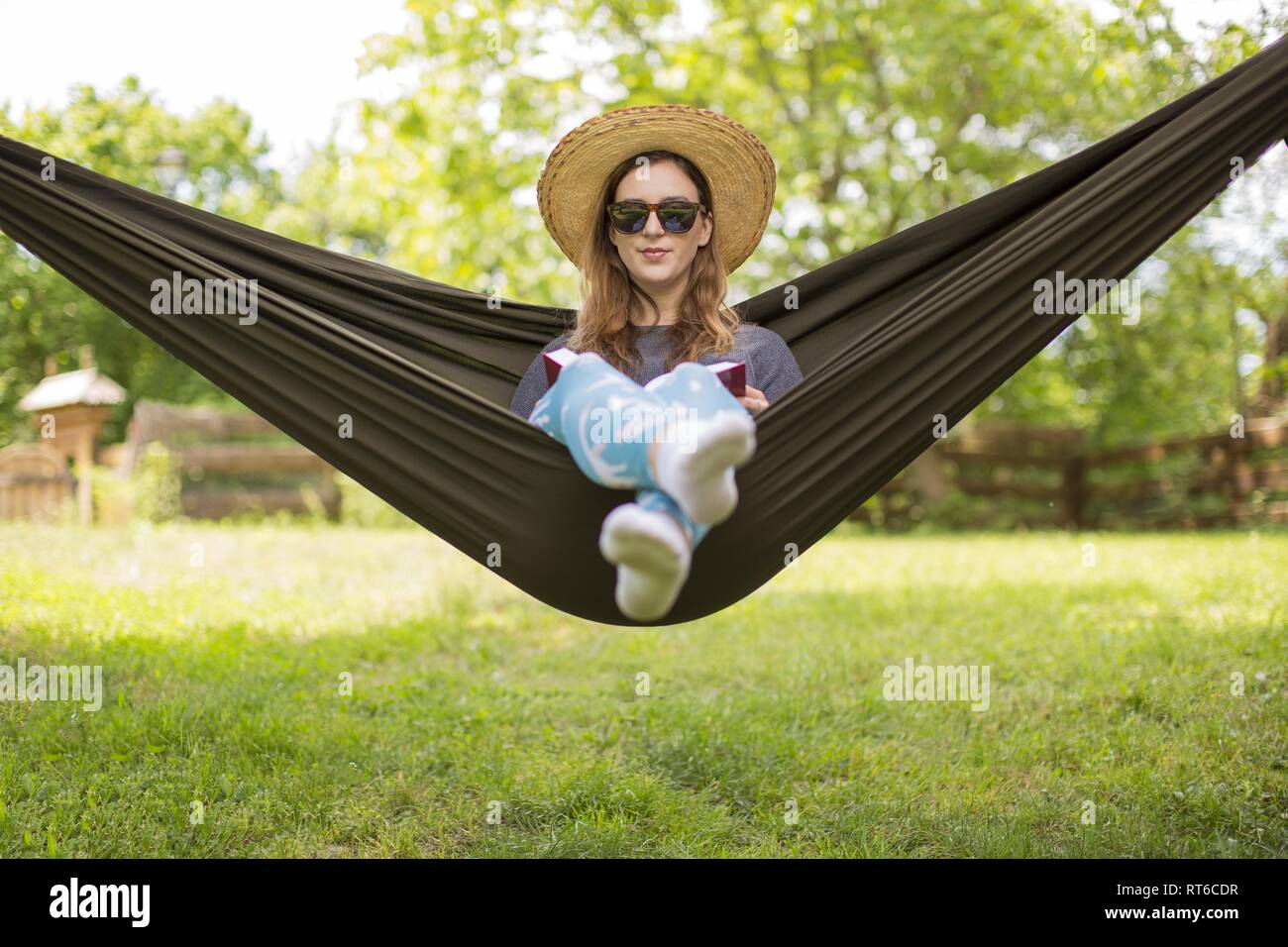 Woman is sitting on a hammock in the park hi-res stock photography and ...